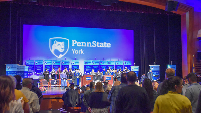 Theatre filled with people watch a commencement ceremony on stage