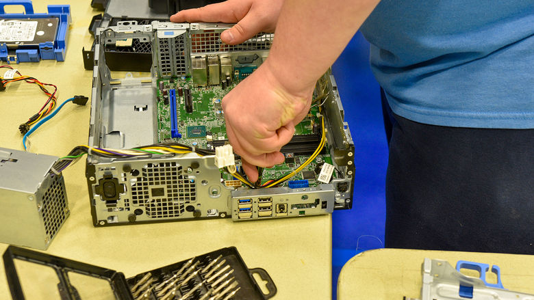 SCROUNGE student disassembling an old desktop for recycling.