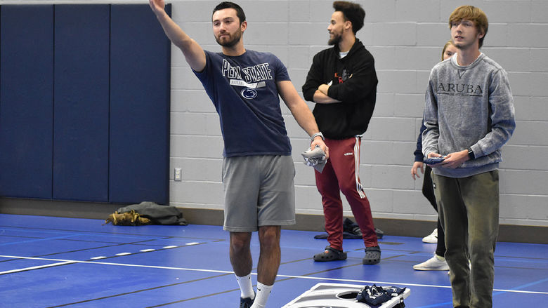 Three young men playing cornhole