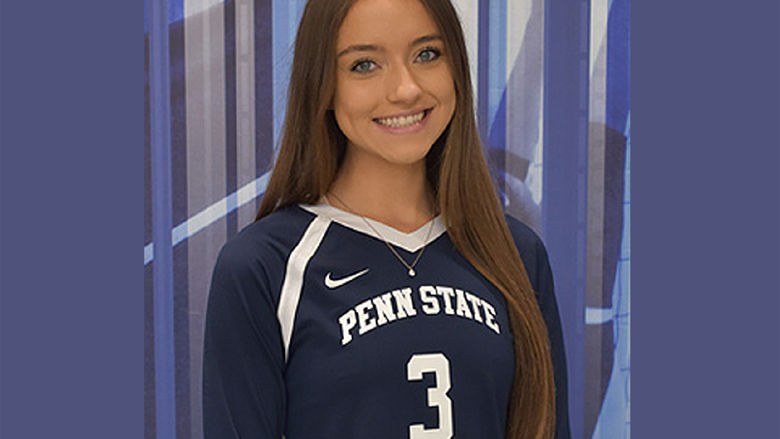 Young female with long brown hair wearing a blue and white Penn State York volleyball jersey.
