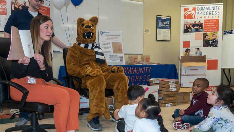 College students and the Nittany Lion mascot read to young children.