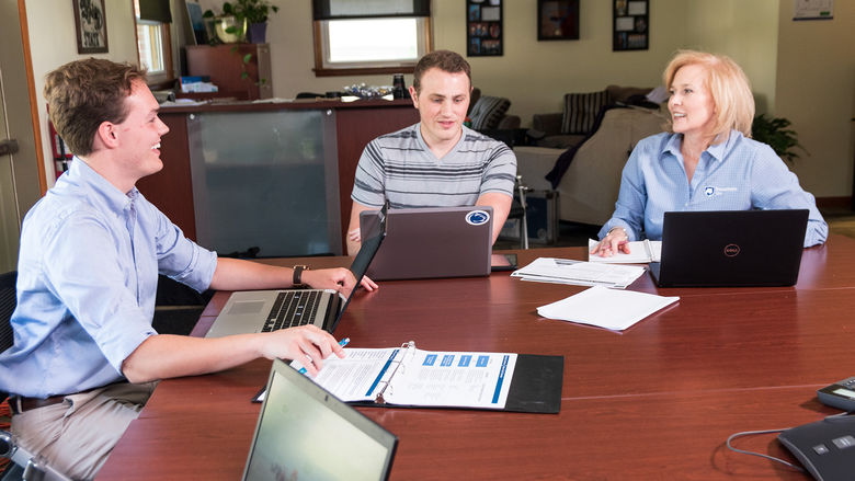 Two students sitting with an adviser during a business meeting.