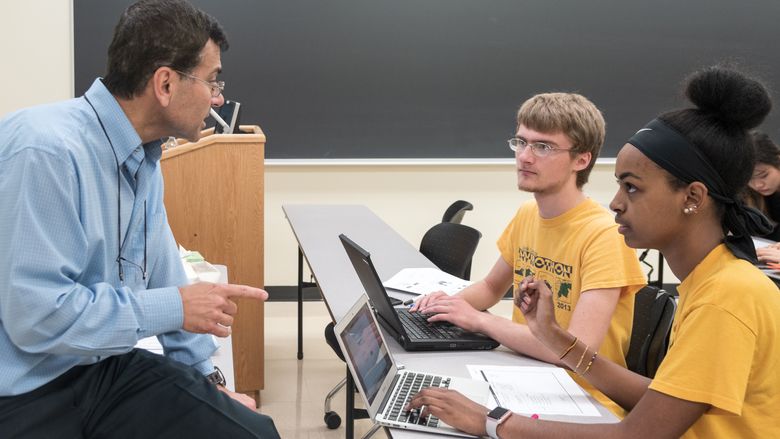 Professor Ali Kara works with a small group of students during a business class.
