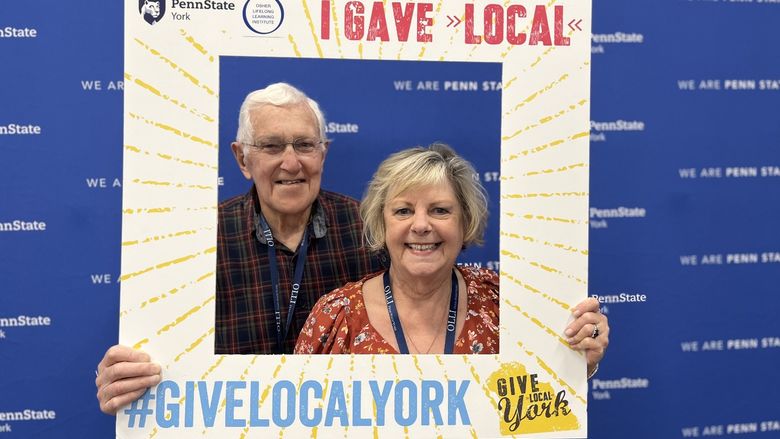 Man and woman holding cutout sign for Give Local York.