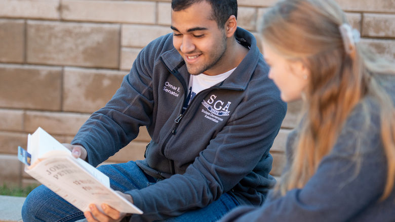 Two students reading a book together.