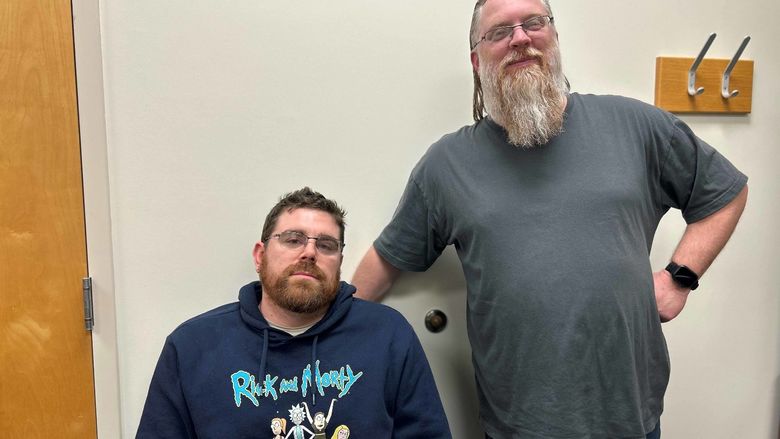 Two men, one sitting and one standing