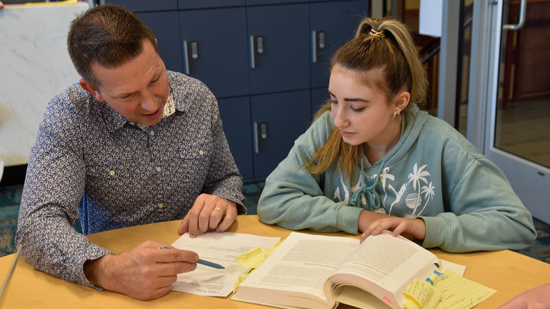 Nittany Success Center - Disability Services mentor sitting at a table with a student reviewing a paper.