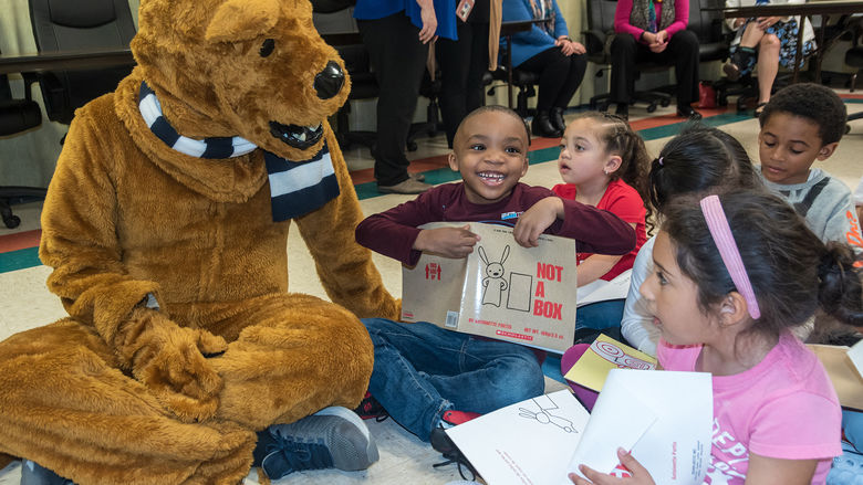 The nittany lion distributing books to children at a local book drive.