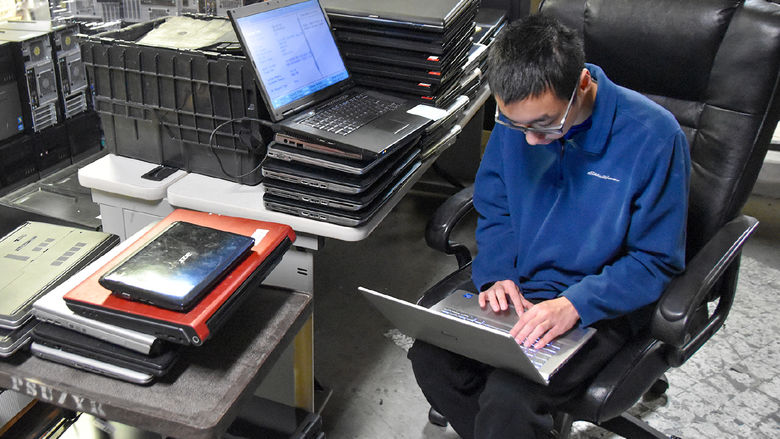 Male student working with a laptop computer in his lap