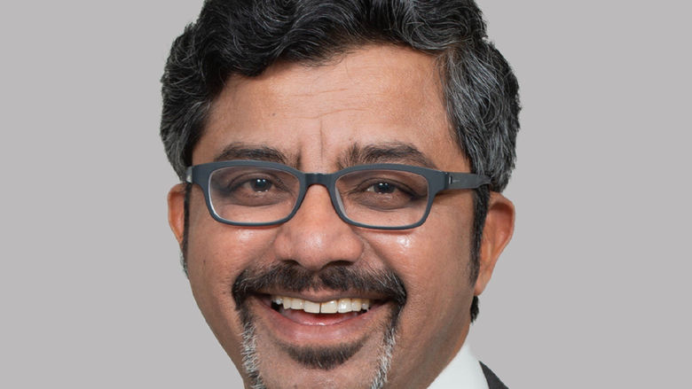 Male adult from India smiling with dark hair and wearing glasses