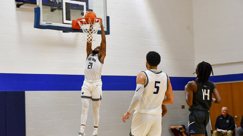 African American basketball player making a slam dunk at the basketball ney, two players watch