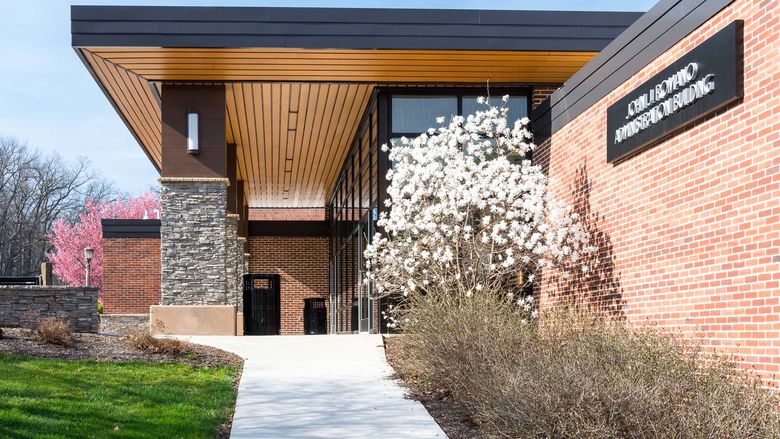 Romano Administration Building with spring-flower trees outside.