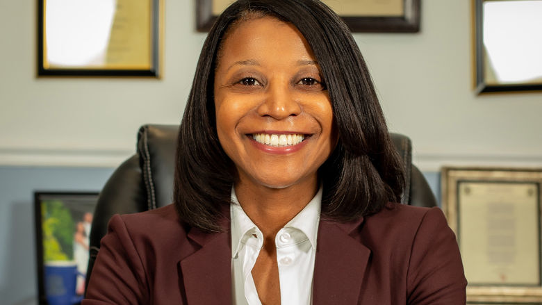 An African American woman with long hair sitting at a desk.