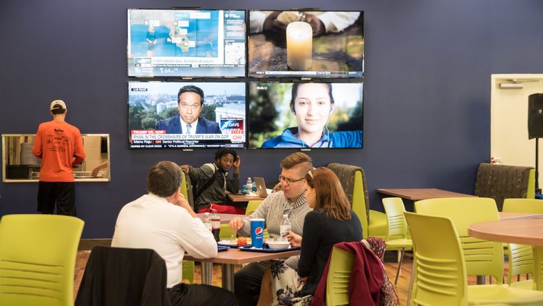 Students sitting in front of a wall of televisions in Rosie’s.