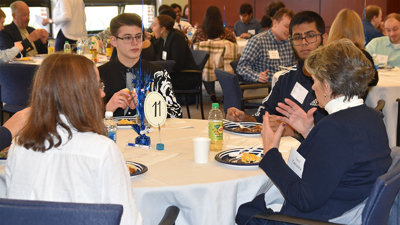 Three students eating with a donor around a roundtable.