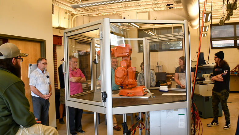 Students and faculty gathered around a robotic arm in the Swenson Engineering Center.