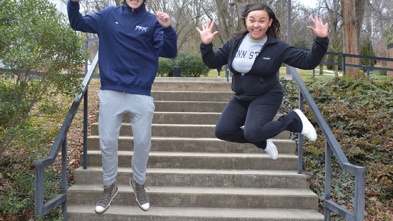 Male and female jump in the air on stepway on campus