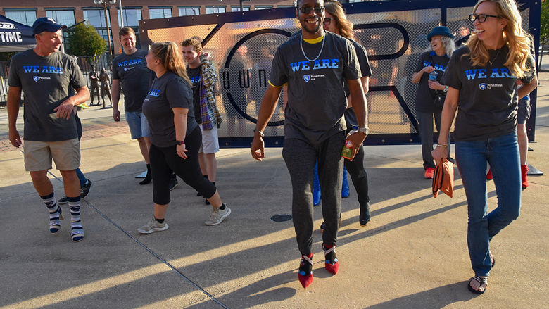 Group of men and women, wearing Penn state York T-shirts, walk wearing high-heeled shoes