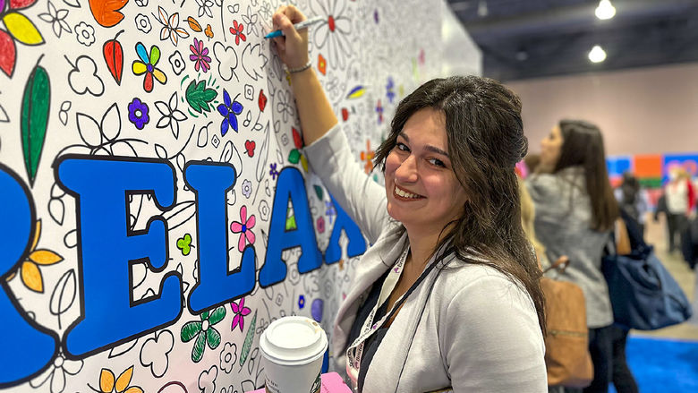 Feamle with long brown hairs colors shapes on a wall during a women's conference in Philadelphia.