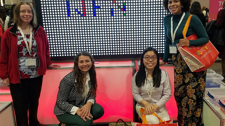 Four young women in front of a light board