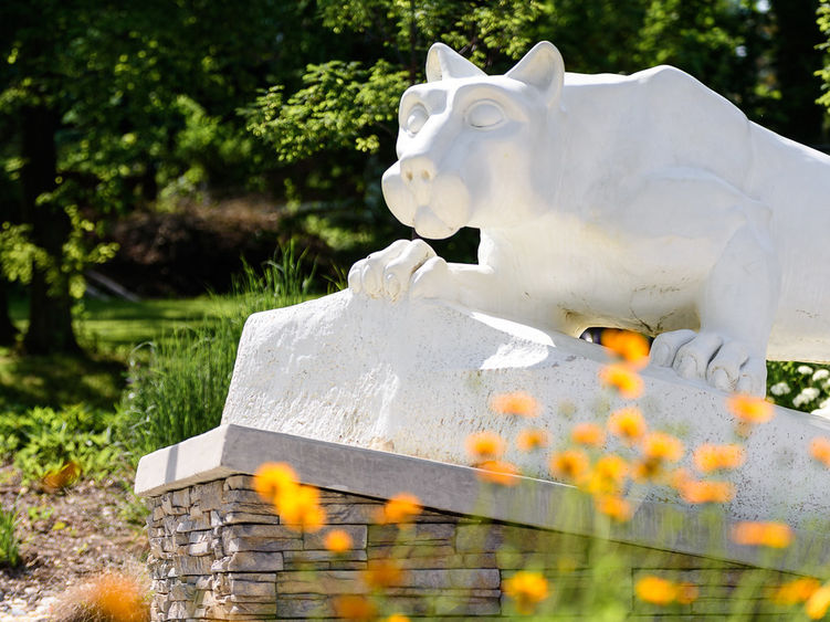 Nittany Lion Statue with spring flowers blooming.
