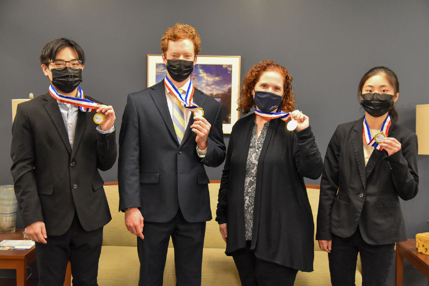 Thee young men and one women, professionally dress, hold first-place medallions