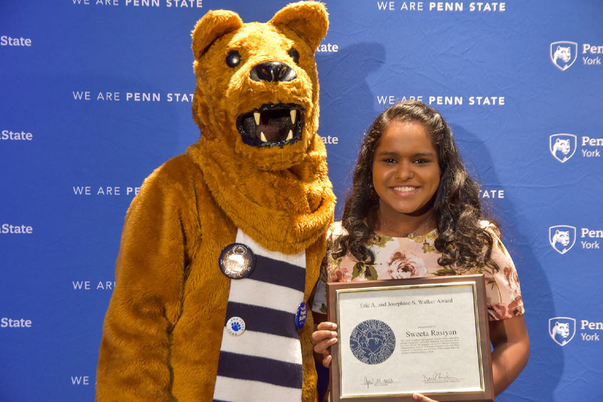 Penn State Nittany Lion and female student pose with award