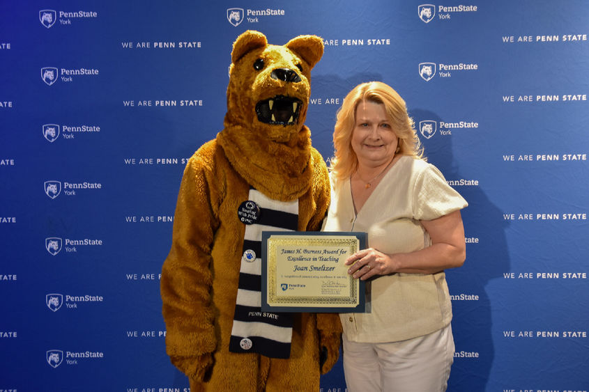 Nittany Lion costumed character presents awatd to female with long blonde hair