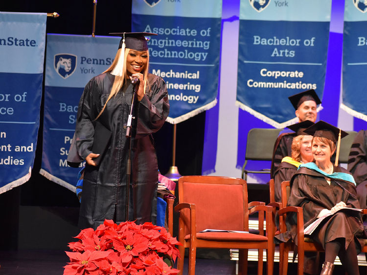 African Amercian female with long hair at microphone during commencement ceremony