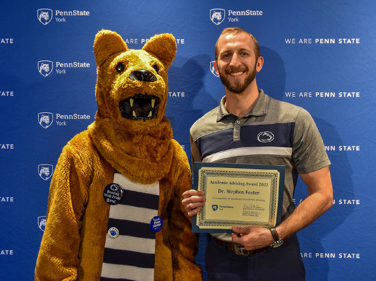 Penn State Nitttany Lion character shows off certificate with male faculty member who received it