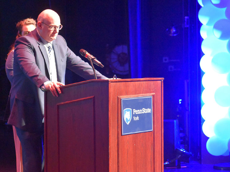 Whhite male coach speaking at podium