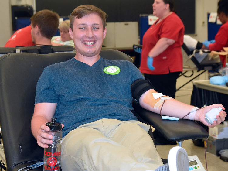 Smiling young caucasian male giving blood during a community blood drive.