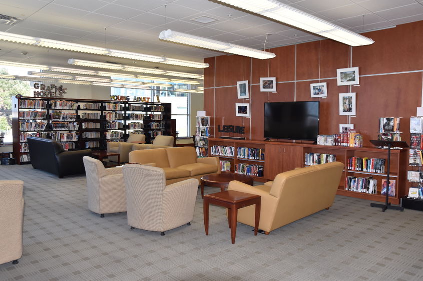 Couches, big screen TV, book stacks, and other chairs in the library.
