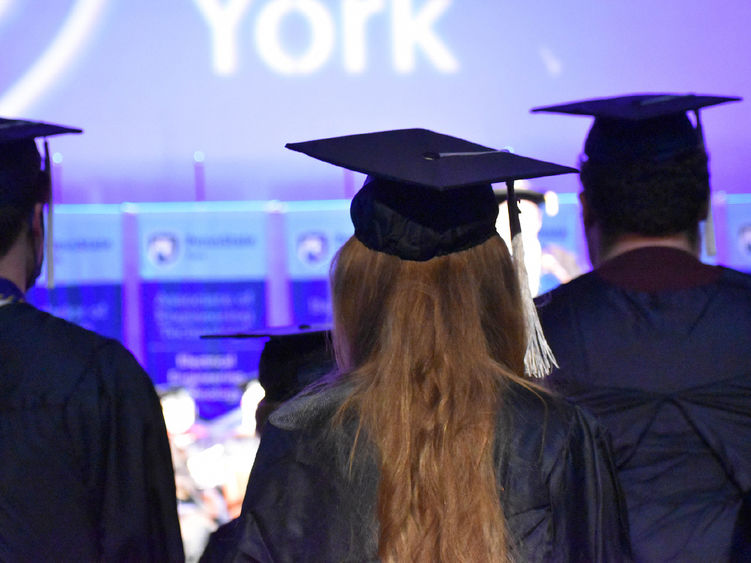 The back of male and female stduents wearing caps and gowns