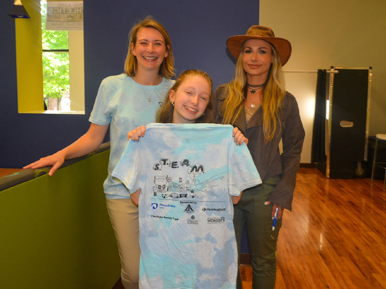 Three females, two older and a young student, show off a T-shirt design for the Pathways program.