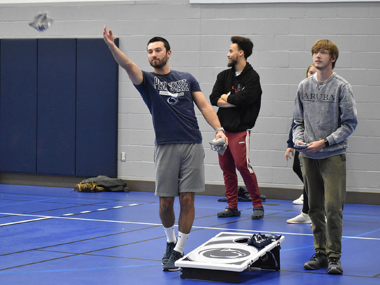 Three young men playing cornhole