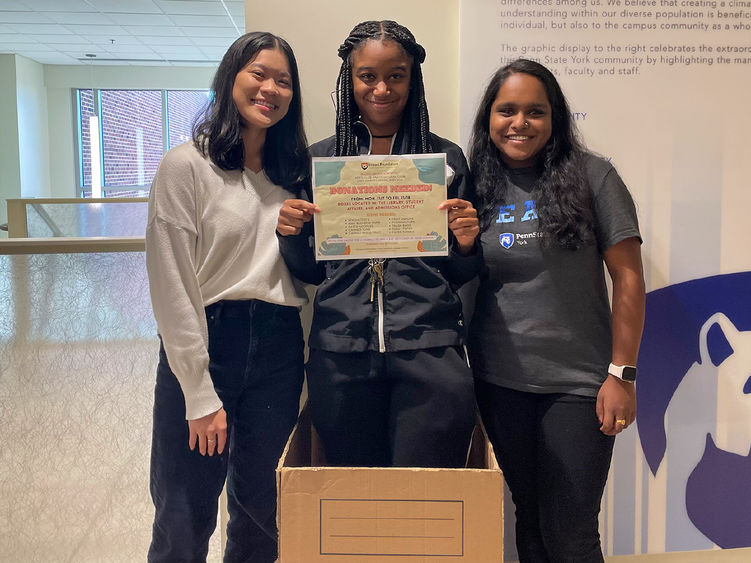 Three ethnic female ethnic Penn State York students promote an upcomig donation drive 