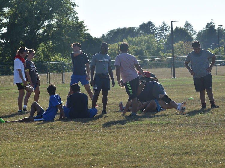 Male African American soccer coach discusses plays with team members during practice