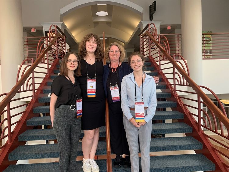 Three students and a faculty member standing on a stairway