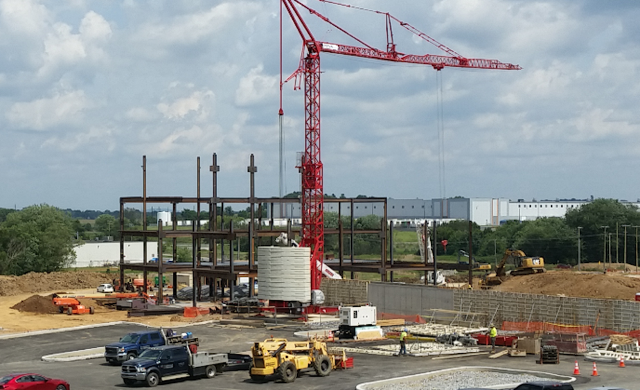 A crane erects steel beams at a hospital construction site