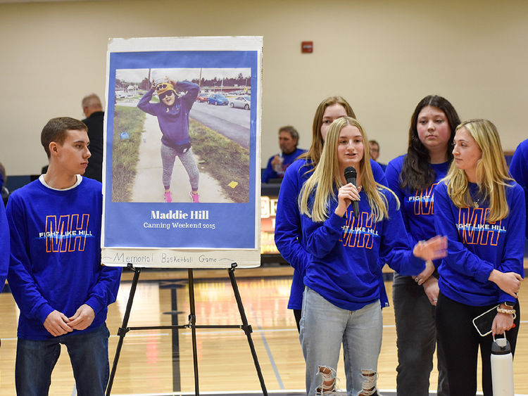 Male and female students on either side of an easel displaying a photo of the late Maddie Hill