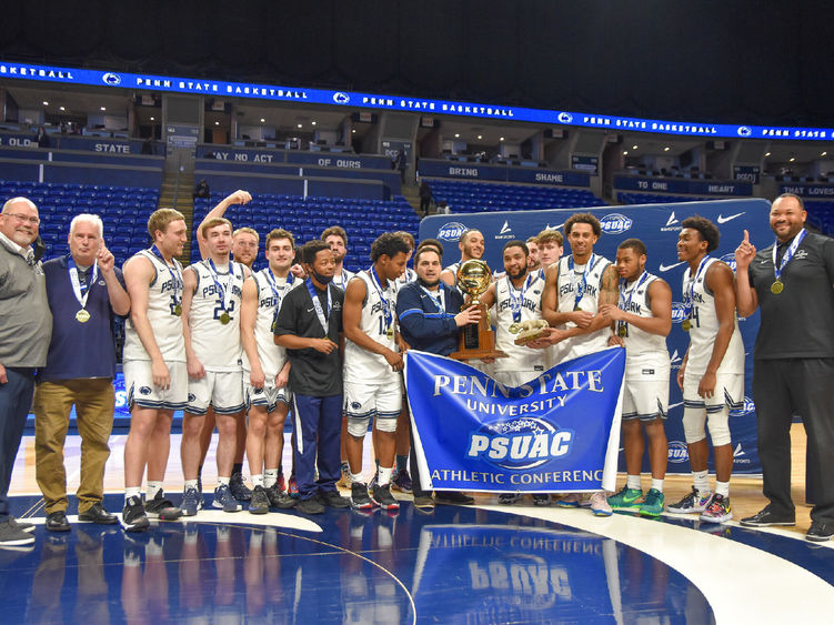 Penn State York men's basketball team celebrates with the championship banner and trophy.
