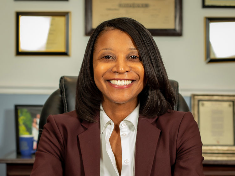 An African American woman with long hair sitting at a desk.