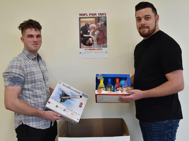 Toys for Tots Collection box with male students each holding a toy to contribute