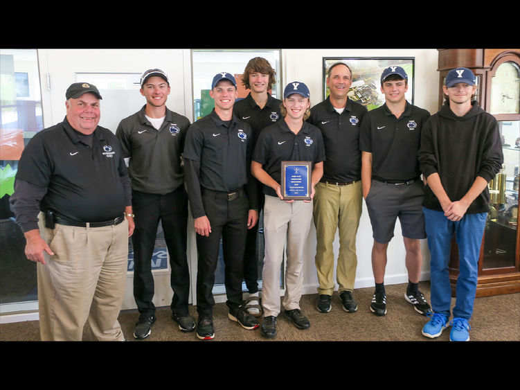 Eight older and younger men with golf trophy.