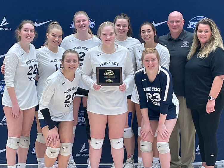 Eight female student-athletes iat Penn State York in volleyball uniforms and a female and male coach pose with award